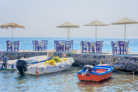 Pier, boats and restaurant tables in Akrotiri, Santorini Island, Greeceの写真素材