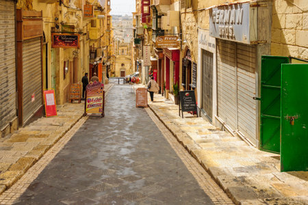 VALLETTA, MALTA - APRIL 13, 2012: Street scene with local businesses, locals and visitors, in Valletta, Maltaのeditorial素材