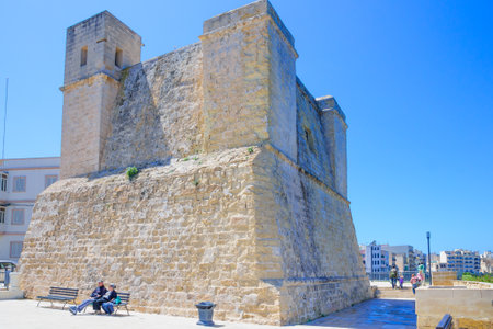 QAWRA, MALTA - APRIL 08, 2012: An old fort building, with locals and visitors, in Qawra, Maltaのeditorial素材