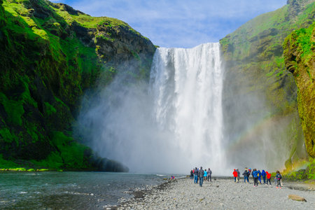 SKOGAR, ICELAND - JUNE 12, 2016: View of the Skogafoss waterfall, with tourists and rainbow, on the Skoga River, in south Icelandのeditorial素材
