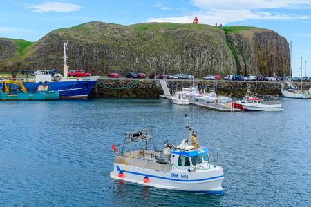 STYKKISHOLMUR, ICELAND - JUNE 20, 2016: Scene of the fishing port, cliff and lighthouse, with locals and visitors, in Stykkisholmur, in the Snaefellsnes peninsula, west Icelandのeditorial素材