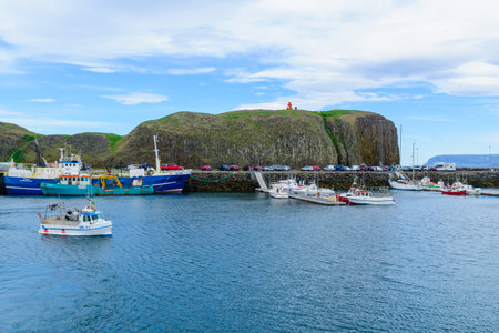 STYKKISHOLMUR, ICELAND - JUNE 20, 2016: Scene of the fishing port, cliff and lighthouse, with locals and visitors, in Stykkisholmur, in the Snaefellsnes peninsula, west Icelandのeditorial素材