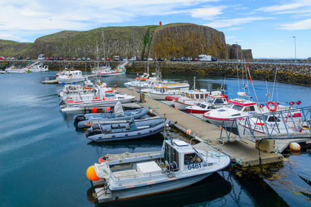 STYKKISHOLMUR, ICELAND - JUNE 20, 2016: Scene of the fishing port, cliff and lighthouse, with locals and visitors, in Stykkisholmur, in the Snaefellsnes peninsula, west Icelandのeditorial素材