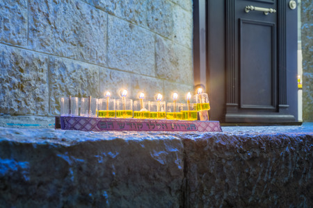 Traditional Menorah (Hanukkah Lamp) with olive oil candles, set for display near the entrance, in the Jewish quarter, Jerusalem Old City, Israel. Text is: These candles are sacredの写真素材