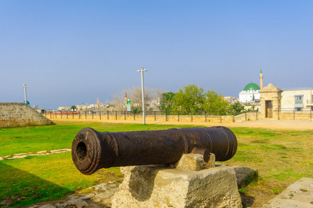 ACRE, ISRAEL - APRIL 27, 2017: Old guns on the city wall promenade, with a visitor and other monuments, in Acre (Akko), Israelのeditorial素材