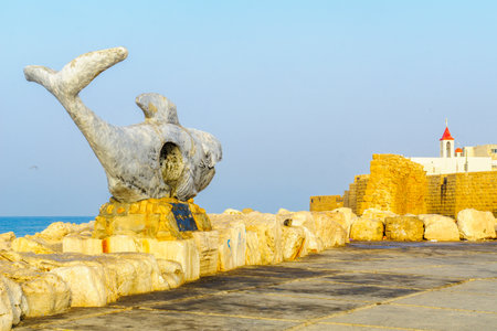 ACRE, ISRAEL - APRIL 27, 2017: A whale monument (for people lost at sea), the old sea wall and St. John the Baptist Franciscan church, in the old city of Acre (Akko), Israelのeditorial素材