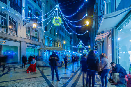 LISBON, PORTUGAL - DECEMBER 28, 2017: Evening scene of Augusta street with Happy Holidays in multiple languages, other Christmas decorations, locals and visitors, in Lisbon, Portugalのeditorial素材