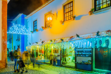 OBIDOS, PORTUGAL - DECEMBER 27, 2017: View of an alley in the old town, with local businesses, Christmas decorations, locals and visitors, in Obidos, Portugalのeditorial素材