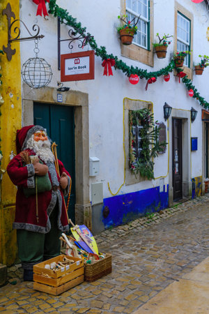OBIDOS, PORTUGAL - DECEMBER 28, 2017: View of an alley in the old town, with local businesses, and Christmas decorations, in Obidos, Portugalのeditorial素材