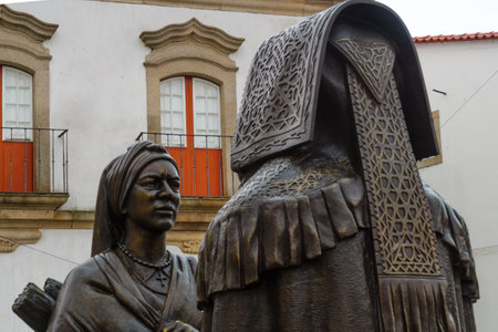 MIRANDA DO DOURO, PORTUGAL - DEC 26, 2017: Bronze statues of Man wearing an Honor Cape and woman with traditional winter clothes (by Jose Antonio Nobre), in the town square. Miranda do Douro, Portugalのeditorial素材