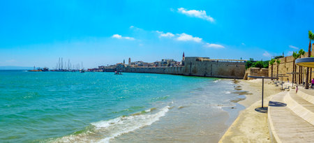 Acre, Israel - July 08, 2019: Panoramic view of the Horses beach, the sea wall and the fishing port, with locals and visitors, in the old city of Acre (Akko), Israelのeditorial素材