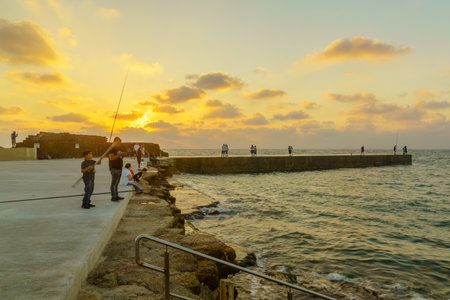 Caesarea, Israel - July 22, 2019: Sunset view of the old port, with fishermen and other visitors, in Caesarea National Park, Northern Israelのeditorial素材