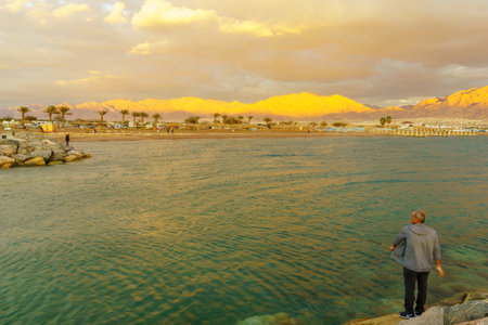 Eilat, Israel - January 17, 2020: Sunset scene of the new marina and hotels, with locals and visitors and Aqaba (Jordan) in the background, in Eilat, southernmost city in Israelのeditorial素材