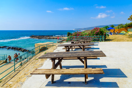Achziv, Israel - July 22, 2020: View of picnic tables and the coast, with visitors, in Achziv national park, northern Israelのeditorial素材