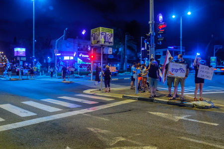 Haifa, Israel - October 10, 2020: People protest within 1km from home, with signs and smartphone light, against the government, Bibi Netanyahu, and the recent lock-down in Ziv center, Haifa, Israelのeditorial素材