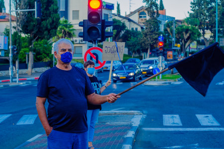Haifa, Israel - October 17, 2020: People with flags and signs are taking part in the Black Flags protest against the government, Bibi Netanyahu, and the recent lock-down in Ziv center, Haifa, Israelのeditorial素材