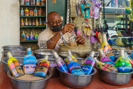 Aqaba, Jordan - October 21, 2021: Street scene with a craftsman preparing glass bottles with colorful sand, in Aqaba, Jordanのeditorial素材