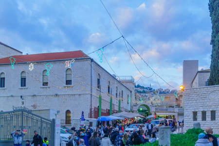 Nazareth, Israel - December 24, 2021: View of and street decorated with Christmas lights, and crowd,...