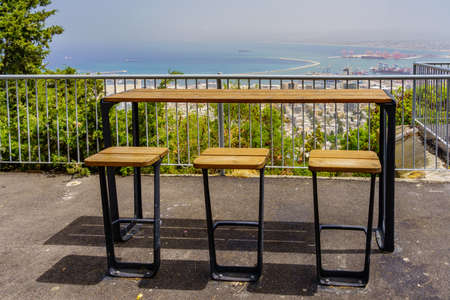 View of a seating area in the promenade, with the port and the Mediterranean Sea in the background, in Haifa, Northern Israelの写真素材
