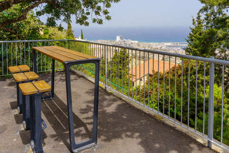 View of a seating area in the promenade, with the port and the Mediterranean Sea in the background,...