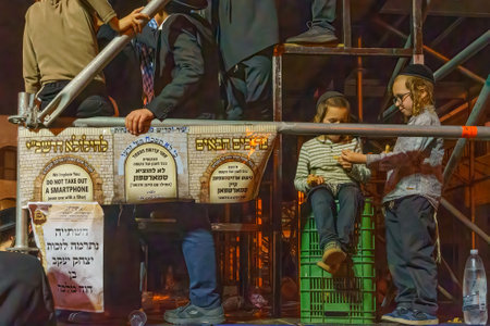 Haifa, Israel - May 18, 2022: Lag BaOmer holyday celebration of the ultra-orthodox Jewish Vizhnitz community, with young men and sign against smartphones. Haifa, Israelのeditorial素材