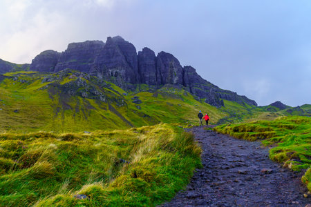 Portree, UK - September 30, 2022: Sunset view of rocks and grass with hikers and the Old Man of Storr, in the Isle of Skye, Inner Hebrides, Scotland, UKのeditorial素材