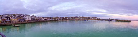 St Ives, UK - October 14, 2022: Panoramic sunset view of the harbor, with various businesses, and the lighthouse, in St Ives, Cornwall, England, UKのeditorial素材