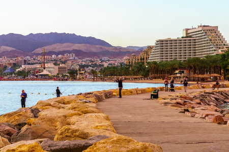 Eilat, Israel - January 15, 2022: Winter sunset view of the marina pier, with visitors and hotel...