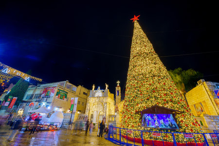 Nazareth, Israel - January 06, 2023: Evening scene of the church (Mary well) square, with Greek Orthodox Church of the Annunciation, Christmas tree, and crowd, Orthodox Christmas Eve, Nazareth, Israelのeditorial素材