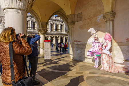 Venice, Italy - February 28, 2022: Couple dressed in traditional costumes, and photographers, in Riva degli Schiavoni waterfront, part of the Venice Mask Carnival, Veneto, Italyのeditorial素材