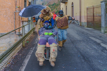 Schignano, Italy - February 18, 2023: Participants in traditional costumes and mask, and spectators, part of the traditional carnival of Schignano, Lake Como, Lombardy, Northern Italyのeditorial素材