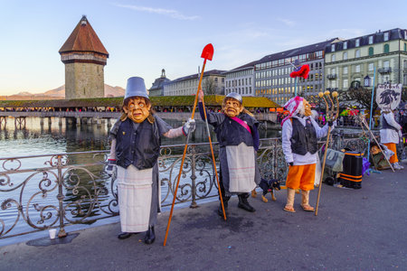 Lucerne, Switzerland - February 20, 2023: Participants in costumes and city monuments in the background, part of the Fasnacht Carnival, in Lucerne (Luzern), Switzerlandのeditorial素材