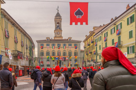 Ivrea, Italy - February 19, 2023: Crowd with red hats, and oranges boxes in the town square (Piazza di Citta), part of the historical carnival of Ivrea, Piedmont, Northern Italyのeditorial素材