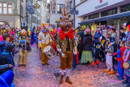 Lucerne, Switzerland - February 21, 2023: Group of participants in costumes march in the streets, and crowd, part of the children parade of the Fasnacht Carnival, in Lucerne (Luzern), Switzerlandのeditorial素材