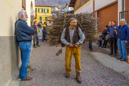 Schignano, Italy - February 18, 2023: Participants in traditional costumes and mask, and spectators, part of the traditional carnival of Schignano, Lake Como, Lombardy, Northern Italyのeditorial素材