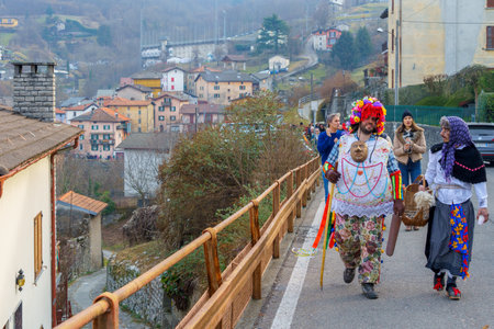 Schignano, Italy - February 18, 2023: Participants in traditional costumes and mask, and spectators, part of the traditional carnival of Schignano, Lake Como, Lombardy, Northern Italyのeditorial素材