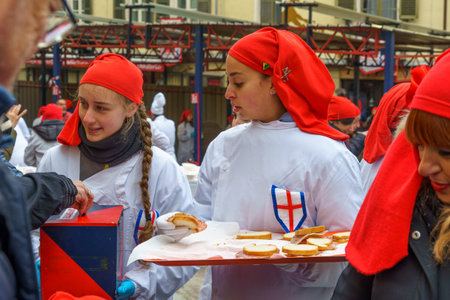 Ivrea, Italy - February 19, 2023: People treating the crowd with food, a tradition that is part of the historical carnival of Ivrea, Piedmont, Northern Italyのeditorial素材