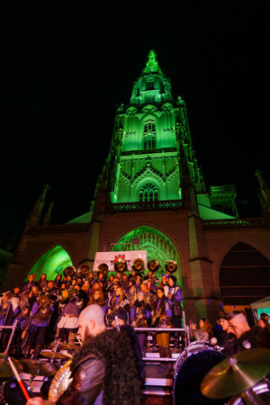 Bern, Switzerland - February 23, 2023: Guggenmusik band in costumes play to the crowd, in front of the cathedral (Berner Munster), part of the carnival of Bern, Switzerlandのeditorial素材