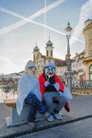 Lucerne, Switzerland - February 20, 2023: Participants in costumes and city monuments in the background, part of the Fasnacht Carnival, in Lucerne (Luzern), Switzerlandのeditorial素材