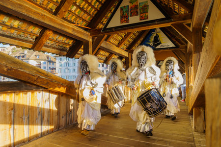 Lucerne, Switzerland - February 20, 2023: Band of musicians in costumes march on the Spreuer bridge, part of the Fasnacht Carnival, in Lucerne (Luzern), Switzerlandのeditorial素材