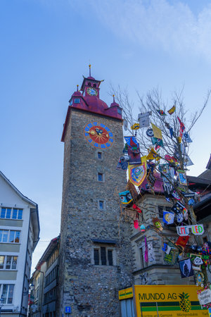 Lucerne, Switzerland - February 22, 2023: View of a clock tower, and tree with carnival decorations, in Lucerne (Luzern), Switzerlandのeditorial素材