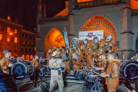 Bern, Switzerland - February 23, 2023: Guggenmusik band in costumes play to the crowd, in front of the cathedral (Berner Munster), part of the carnival of Bern, Switzerlandのeditorial素材