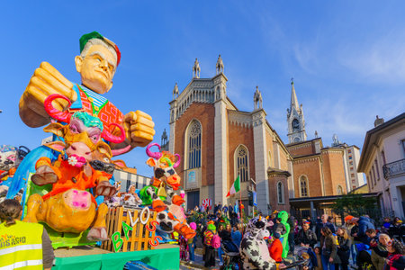 Cantu, Italy - February 25, 2023: Carnival parade, with the Italian Cows figure wagon, crowd and the Church of Saints Michael and Blaise, in Cantu, Lombardy, Northern Italyのeditorial素材