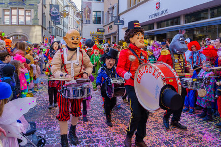 Lucerne, Switzerland - February 21, 2023: Group of participants in costumes march in the streets, and crowd, part of the children parade of the Fasnacht Carnival, in Lucerne (Luzern), Switzerlandのeditorial素材