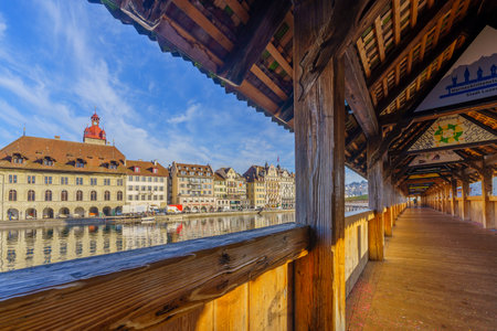 Lucerne, Switzerland - February 22, 2023: View from the Chapel Bridge, the Reuss River and various buildings, in Lucerne (Luzern), Switzerland (paintings are of carnival)のeditorial素材
