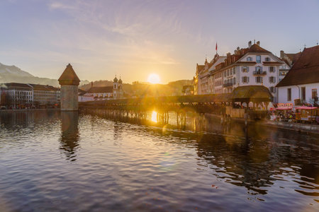 Lucerne, Switzerland - February 20, 2023: Sunset view of the Chapel Bridge, and the Reuss River, with other buildings, locals, and visitors, in Lucerne (Luzern), Switzerlandのeditorial素材