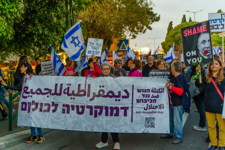 Haifa, Israel - April 22, 2023: Protest march with various banners, signs, and flags as...