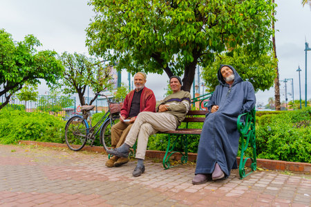 Marrakesh, Morocco - April 05, 2023: View of group of locals sitting on a bench, in Marrakesh, Moroccoのeditorial素材