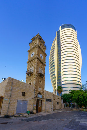 Haifa, Israel - May 04, 2023: View of the Minaret and clock tower of the Al Jarina Mosque (Jurayneh Ottoman Mosque, the Big Mosque), with modern office buildings, in Haifa, Israelのeditorial素材