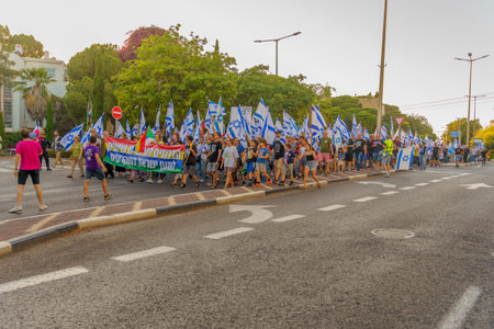 Haifa, Israel - June 24, 2023: People marching with flags and various signs. Week 25 of anti-government protest in Haifa, Israelのeditorial素材